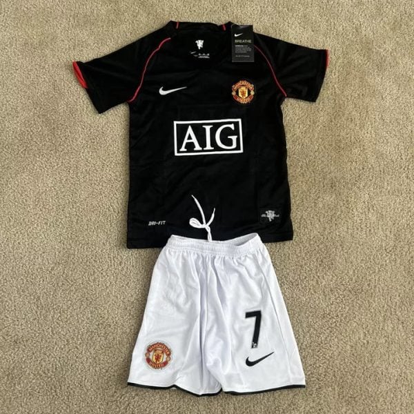 Manchester United kit laid out: black jersey with red piping, white Nike swoosh, AIG sponsor, and white shorts with the number 7 and club crest.