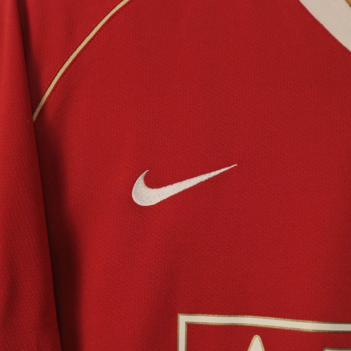 Red sports jersey fabric with a white Nike swoosh logo visible on the lower right edge.