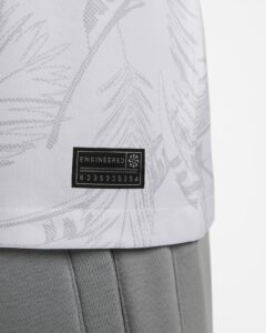 Close-up of light fabric with a black rectangular patch reading 'ENGINEERED' and a small emblem.