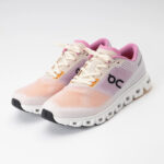 Pair of peach-pink knit running shoes with cream laces and a chunky white sole, side logo visible on the lateral side.