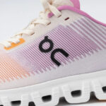 Close-up of a pastel pink and white running shoe with the On logo on the side