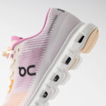 Pastel pink gradient On running shoe with knit upper and chunky white sole, shown in side angle.