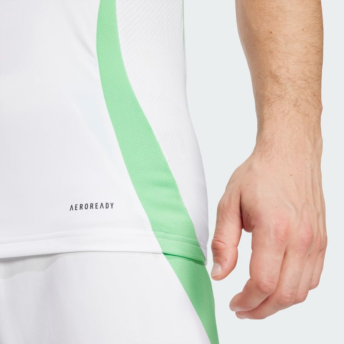 Close-up of a person wearing white athletic apparel with a mint-green diagonal stripe, hand resting beside the fabric.