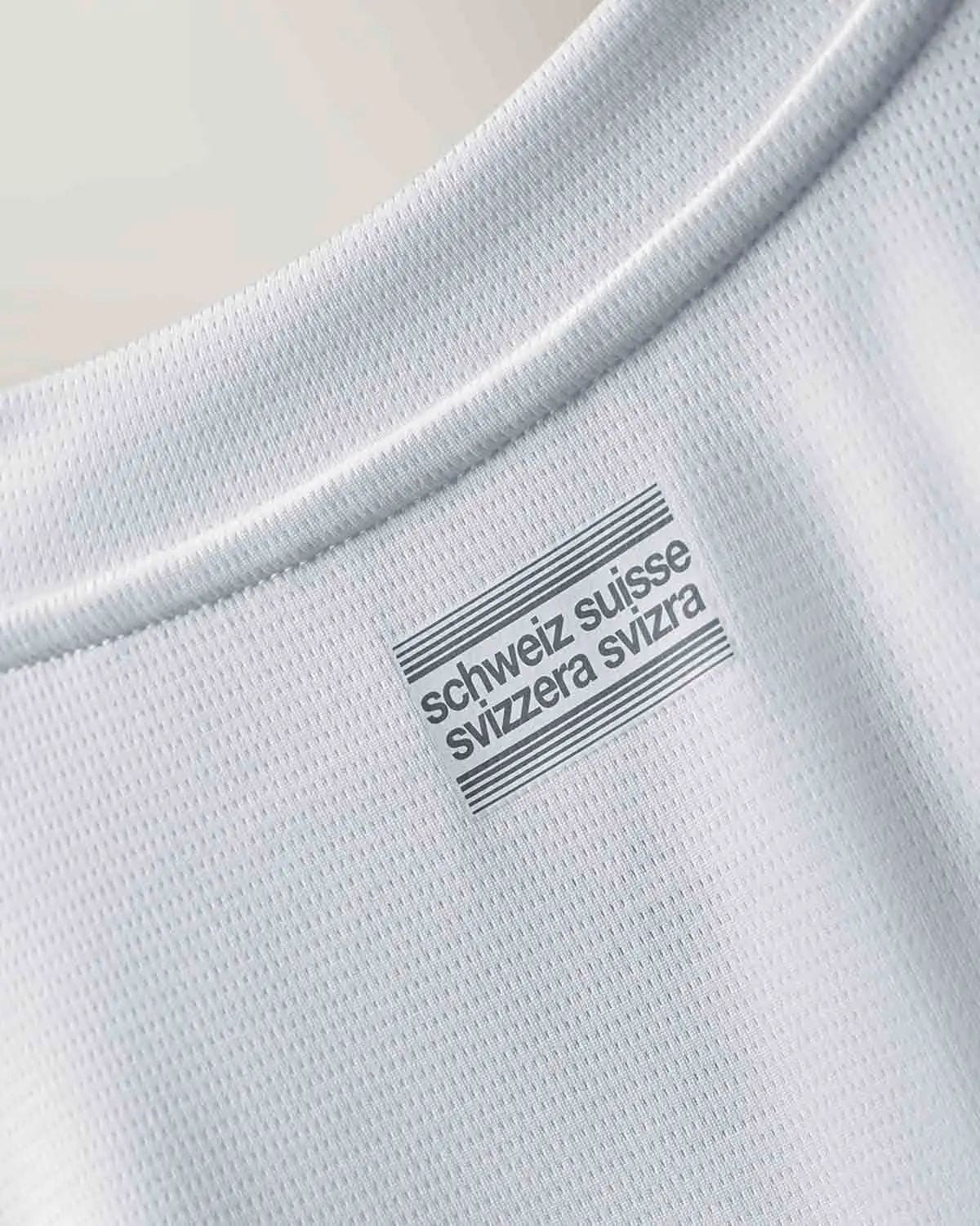 tK1sfFU6fIaGTg0 | UAE SPORT STORE Close-up of white fabric with a barcode-style label that reads 'schweiz suisse svizzera svizzera' (origin/brand tag)