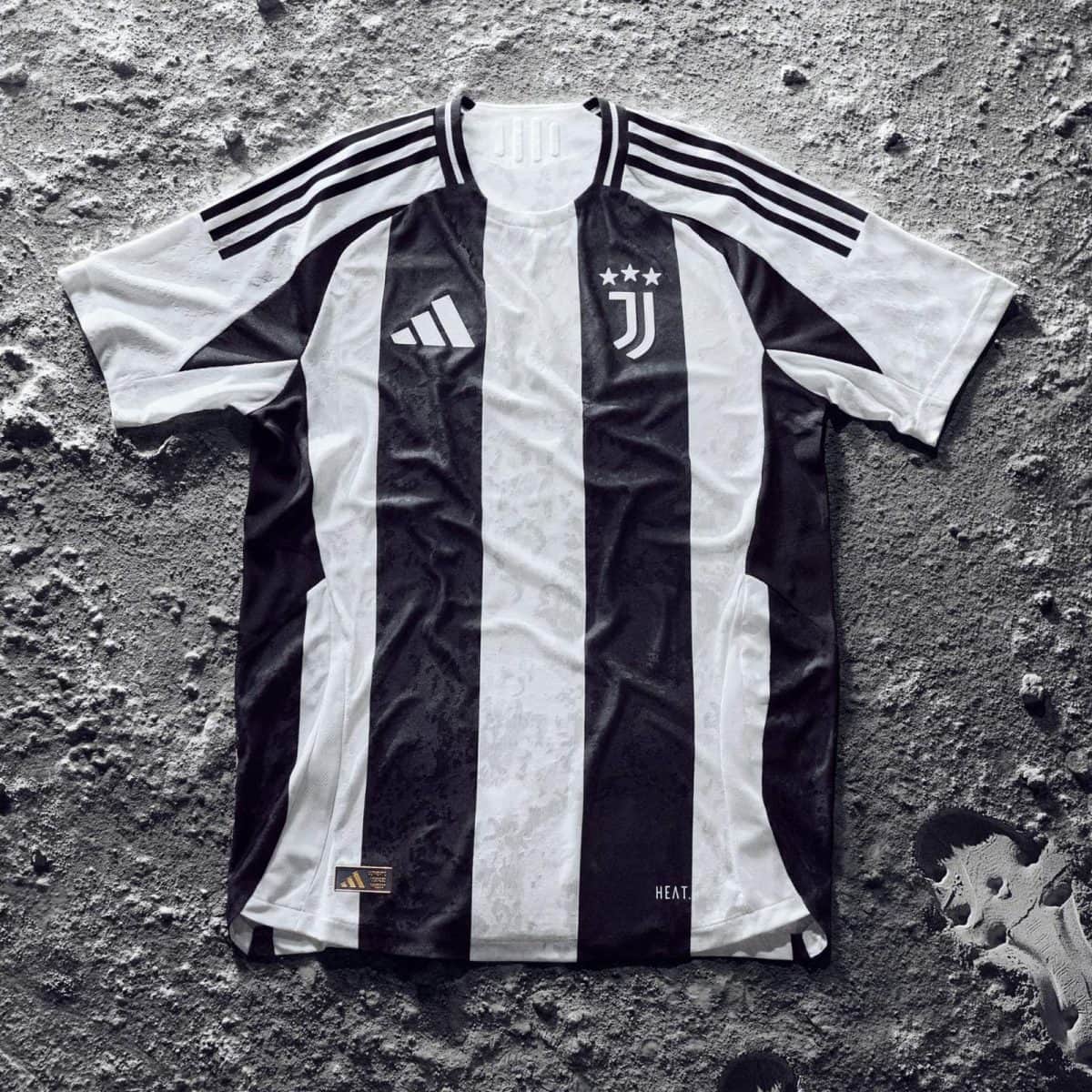 Juventus black-and-white striped soccer jersey laid flat on a rough gray surface, with Adidas logo and three shoulder stripes visible.
