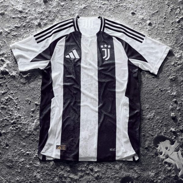 Juventus black-and-white striped soccer jersey with crest and stars laid flat on a rough gray surface