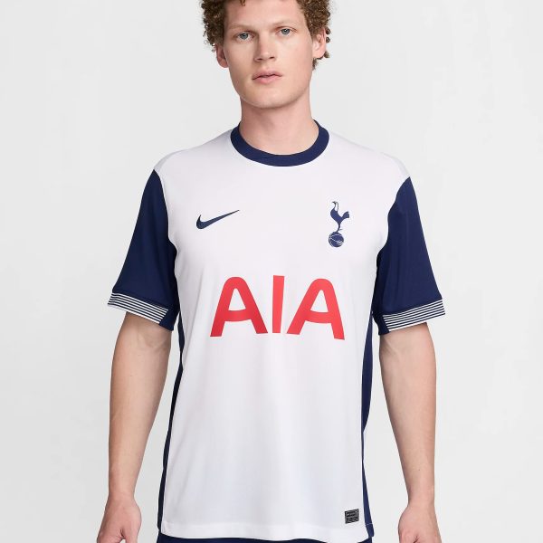 Male model wearing a white and navy Tottenham Hotspur jersey with the AIA sponsor, shown from the chest up against a light background.
