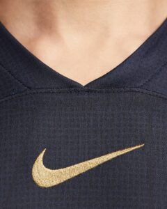 Close-up of dark blue fabric with a gold Nike swoosh embroidered on it.