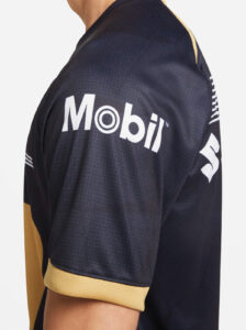Close-up of a navy sports jersey with a white Mobil logo on the sleeve and gold trim at the cuff.