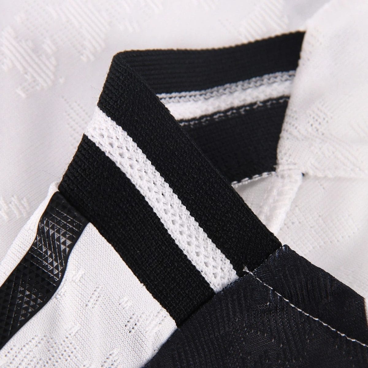Close-up of a black woven strap with a white stripe against a textured white background.