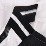 Close-up of a black woven strap with a white stripe against a textured white background.