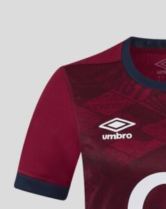 Close-up of a maroon Umbro jersey showing the shoulder seam, navy collar, and partial white logo.