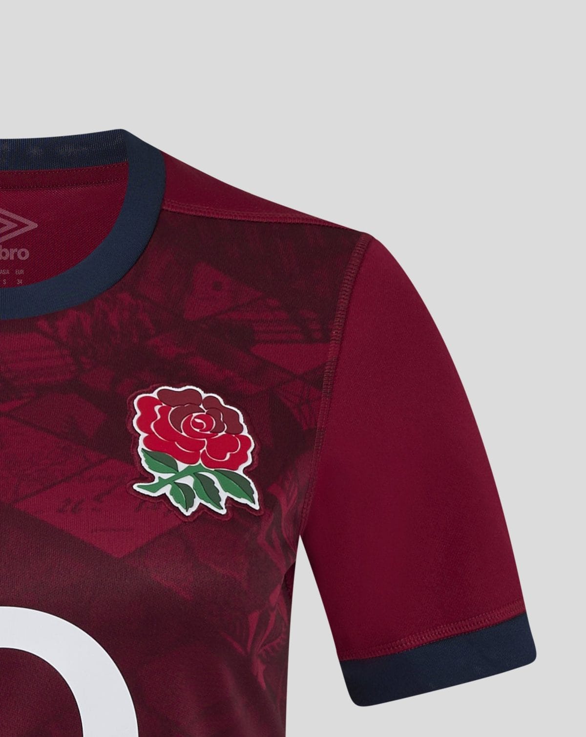 Close-up of a maroon sports jersey with a red rose badge on the chest and a navy collar and sleeve cuff.