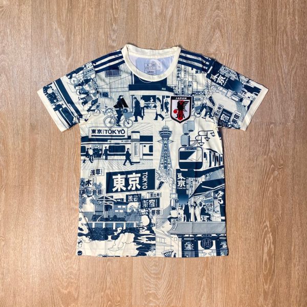 White T-shirt with a blue Tokyo-cityscape collage print laid on a wooden floor.