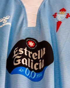 Close-up of a light blue football jersey with the Estrella Galicia sponsor logo and the club crest.