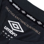 Umbro logo on a black fabric with the slogan 'TOGETHER ANYTHING IS POSSIBLE' visible and branded collar detailing above.