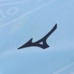 Close-up of a dark blue abstract sports logo on light blue fabric.