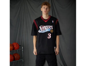 width_538_height_415_quality_90_fit_pad_format_webp | UAE SPORT STORE Male model wearing a black basketball jersey with 'Sixers' logo and number 3, standing in a studio with basketballs on a rack nearby.