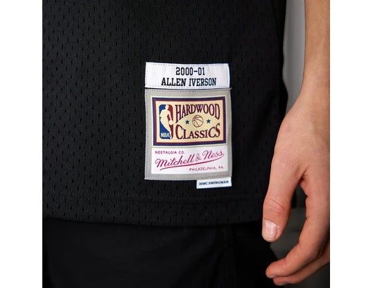 width_538_height_415_quality_90_fit_pad_format_webp_4 | UAE SPORT STORE Close-up of black mesh basketball jersey with stacked patches: '2000-01 Allen Iverson' and Hardwood Classics by Mitchell & Ness.