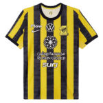 Soccer jersey with vertical yellow and black stripes, club crest on the left chest, and sponsor logos across the front.