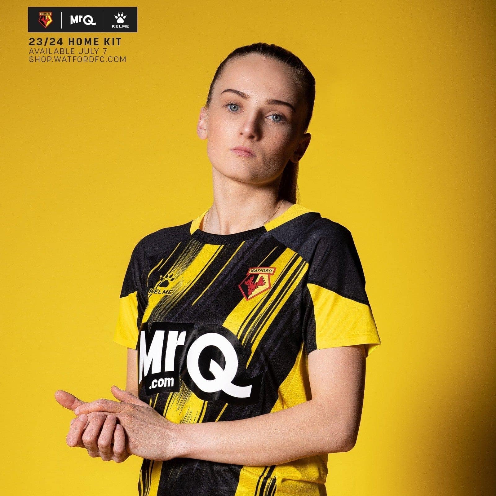 x6hK6MGScGzJxTG_8c01b6b2-8a4e-4c71-8bb9-d8f4e65608f4 | UAE SPORT STORE Portrait of a woman wearing Watford 23/24 home kit against a solid yellow background, hands softly clasped in front.