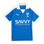 Blue soccer jersey with white collar and sleeve trim, featuring Puma logo, Al Hilal crest, and SAVVY Games Group sponsor.
