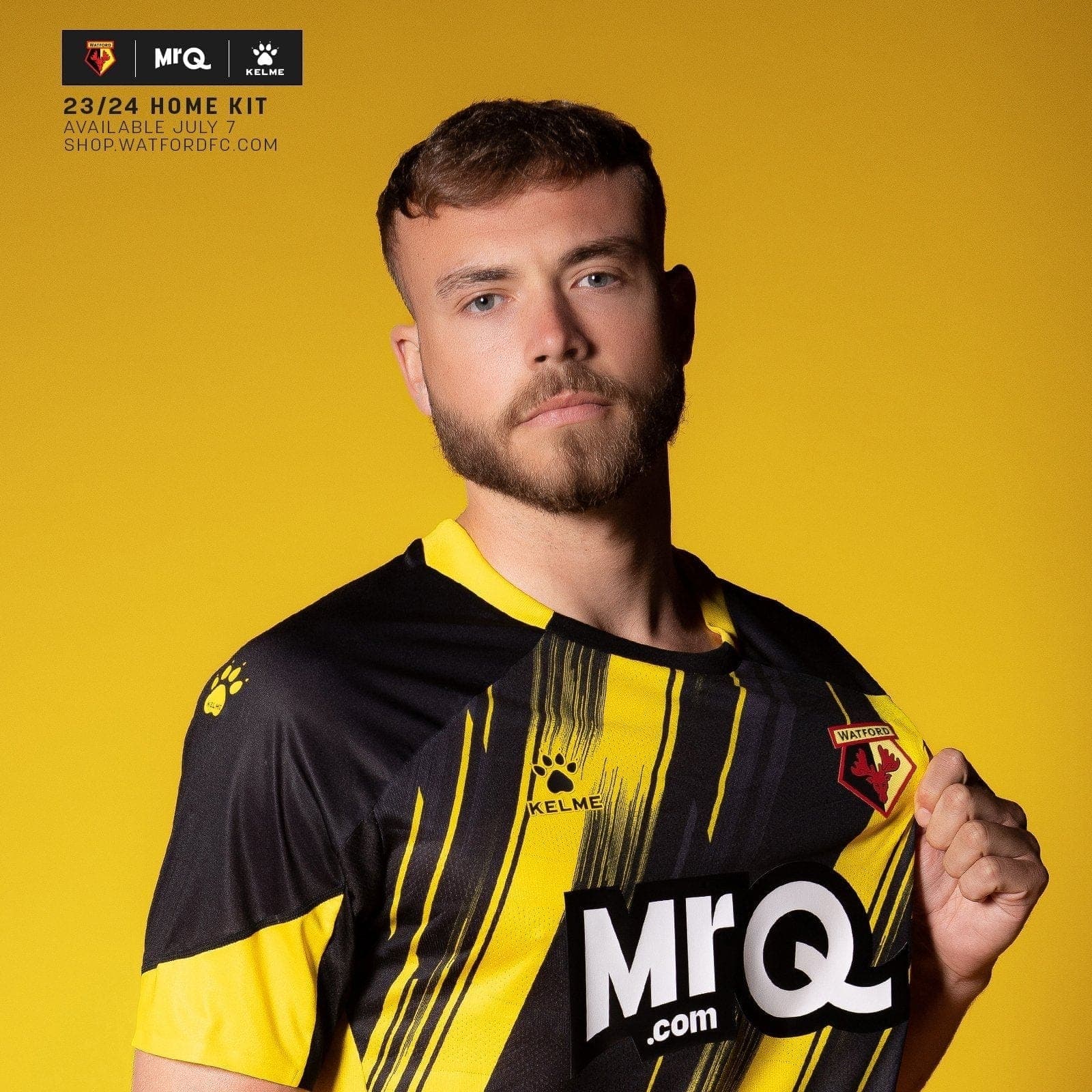 xL2ZO1x35UM3iJt_4917adbc-f190-4b18-91cb-a408f4ead10b | UAE SPORT STORE Portrait of a man with short brown hair and a beard wearing a black-and-yellow Watford jersey on a solid yellow background.