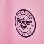 Embroidered Brentford Football Club crest on pink fabric, featuring a bee at the center.