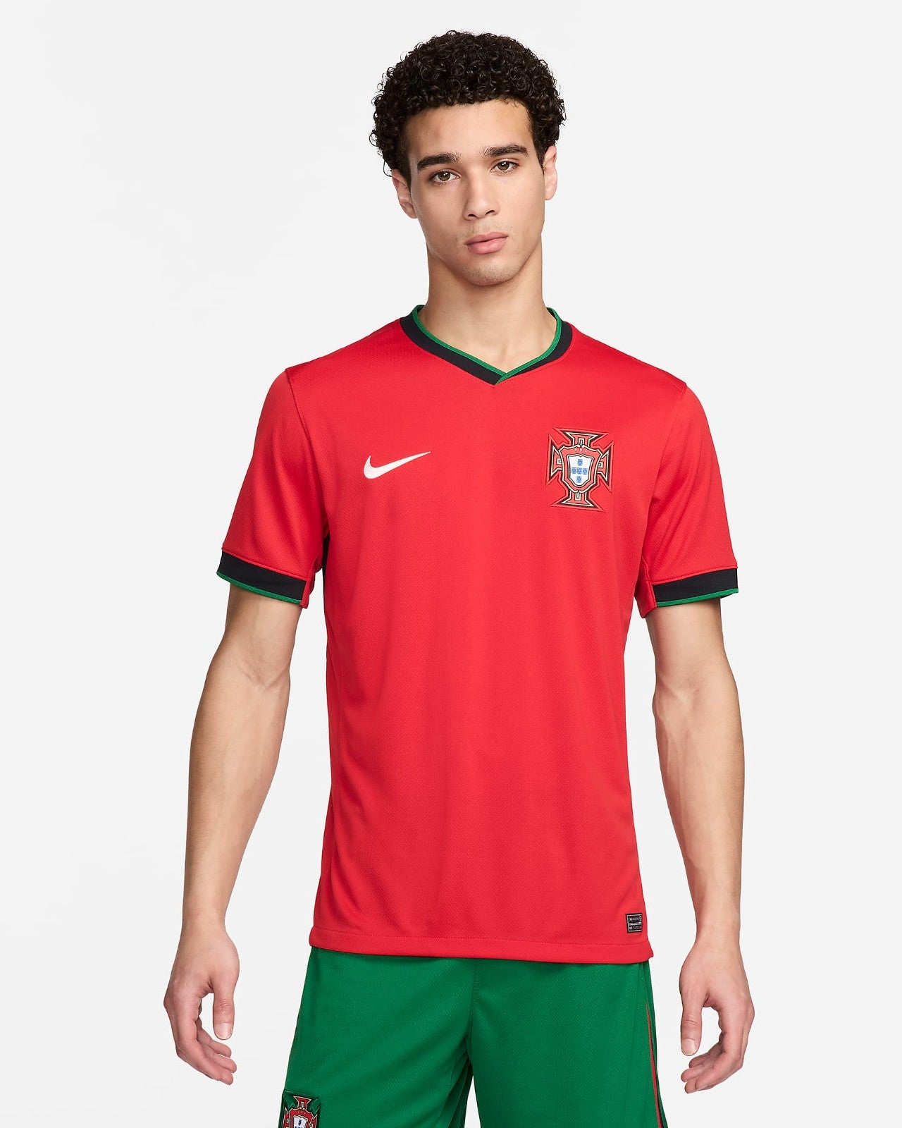 xTiJgnfohcRAcEp | UAE SPORT STORE Male model wearing a red Portugal national team jersey with a green-trim V-neck, white Nike swoosh, and crest, facing the camera.