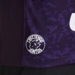 Close-up of purple patterned fabric with a white circular logo of a dog and surrounding text.