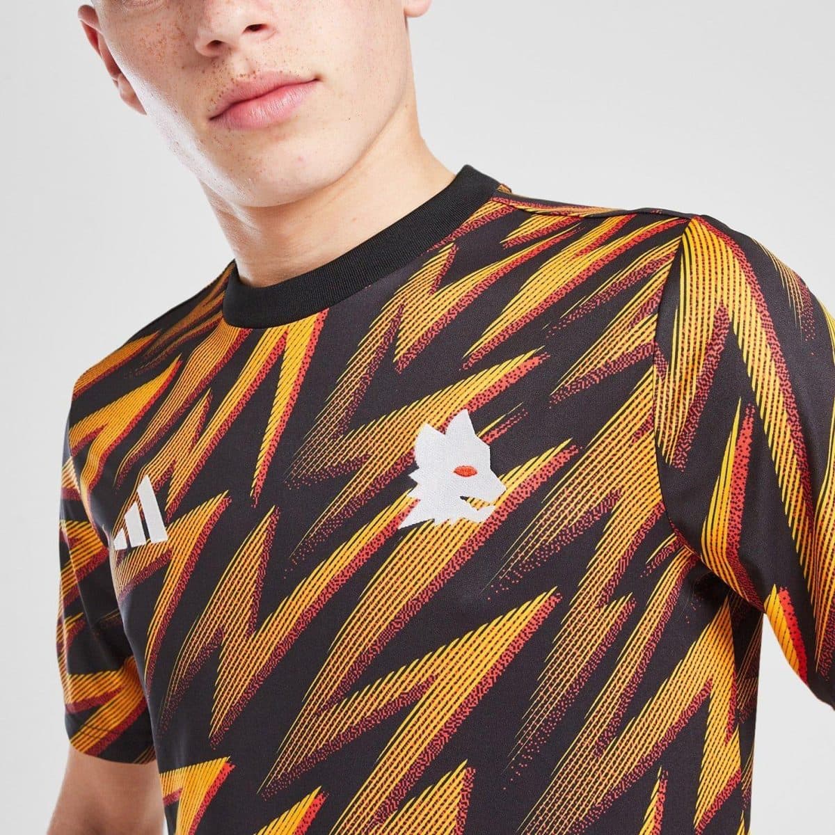Close-up of a person wearing a black T-shirt with bold yellow and red diagonal abstract stripes and a white logo on the chest area.