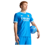 Soccer player in blue Real Madrid away kit holding a blue ball under his arm, ready for action.