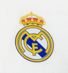 Partial Real Madrid crest with crown on a white background, cropped to show the top of the emblem.