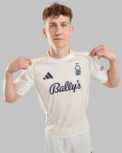 Young man in a white Nottingham Forest football jersey shows the Bally's sponsor logo and club crest.