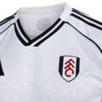 y9 | UAE SPORT STORE Close-up of a white Fulham FC football jersey with black trim and the FFC crest on the left chest.