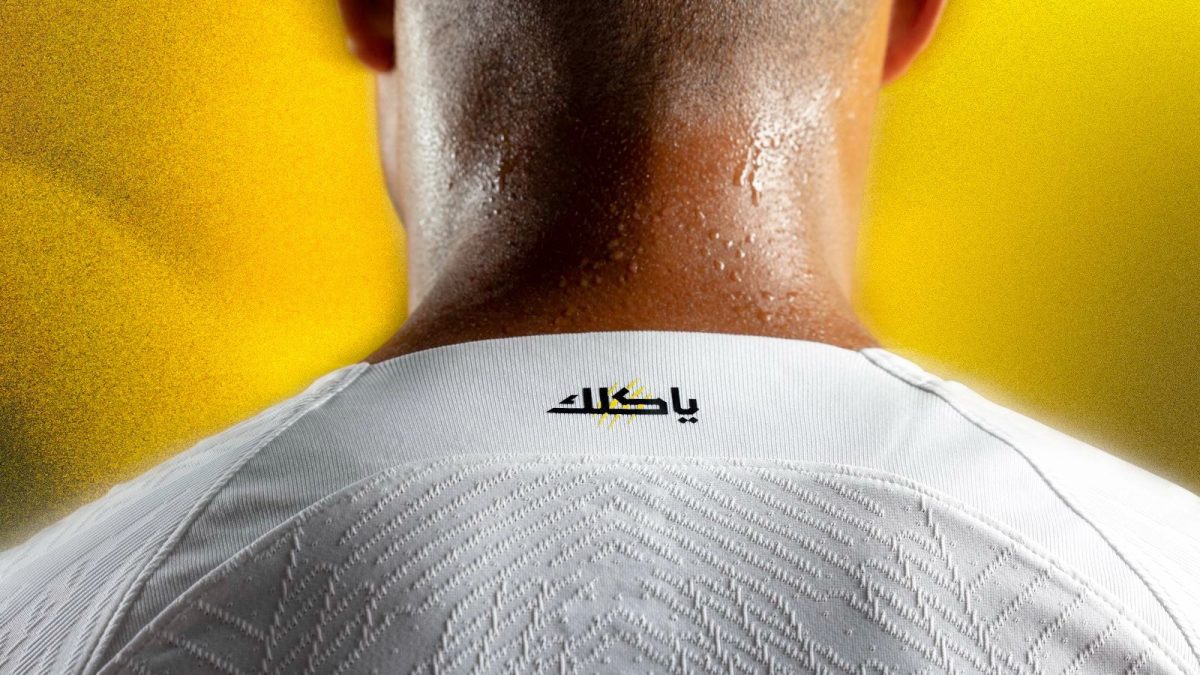Close-up of the back of a neck wearing a white sports jersey with a small logo at the collar against a yellow background.