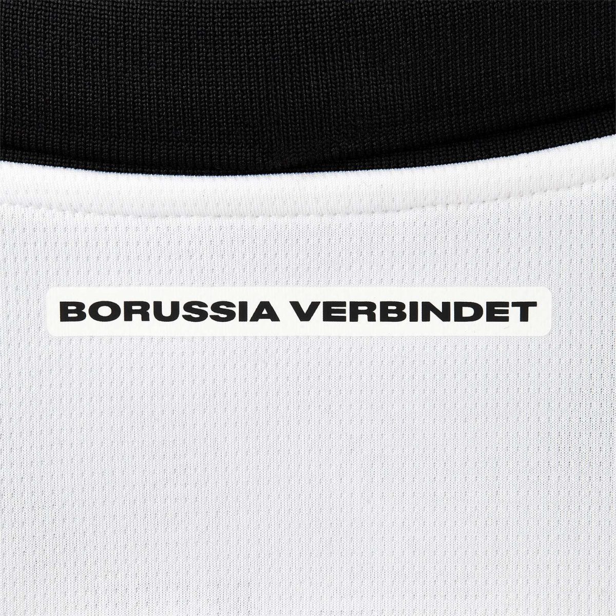 Close-up of black and white knit fabric with a white label reading 'BORUSSIA VERBINDT'.
