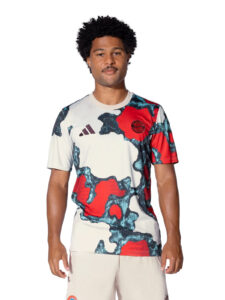 Male model wearing a white, red, and teal camouflage-pattern soccer jersey with Adidas logo and a circular team crest on the chest (front view).