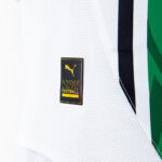 Close-up of a white perforated sports jersey with a small black-and-gold patch featuring the Puma logo and the words 'AUTHENTIC' and 'FOOTBALL'.