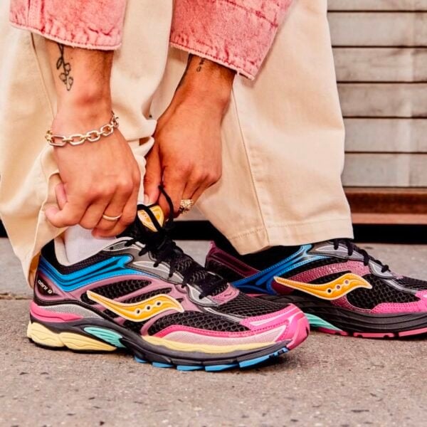 Person wearing Saucony ProGrid Omni 9 running shoes in black, pink, blue, and yellow.