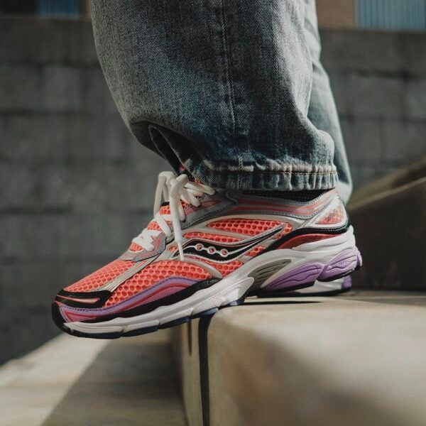 Close-up of pink, purple, and white Saucony ProGrid Omni 9 running shoes on a person's foot.