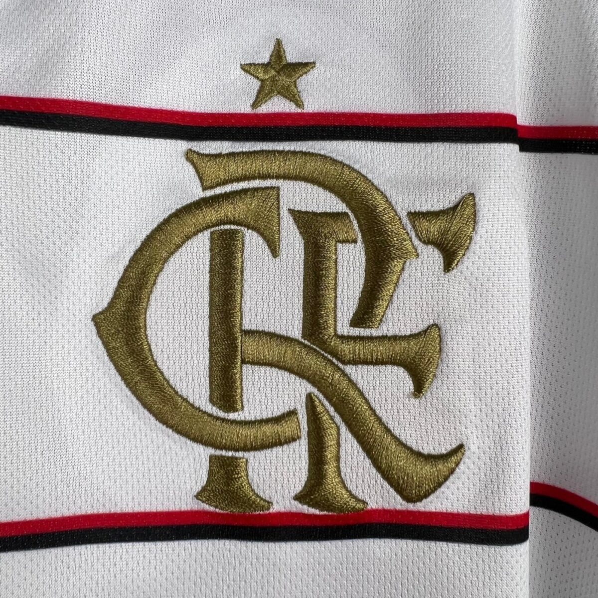 Close-up of Flamengo football club crest on jersey fabric with gold embroidery.