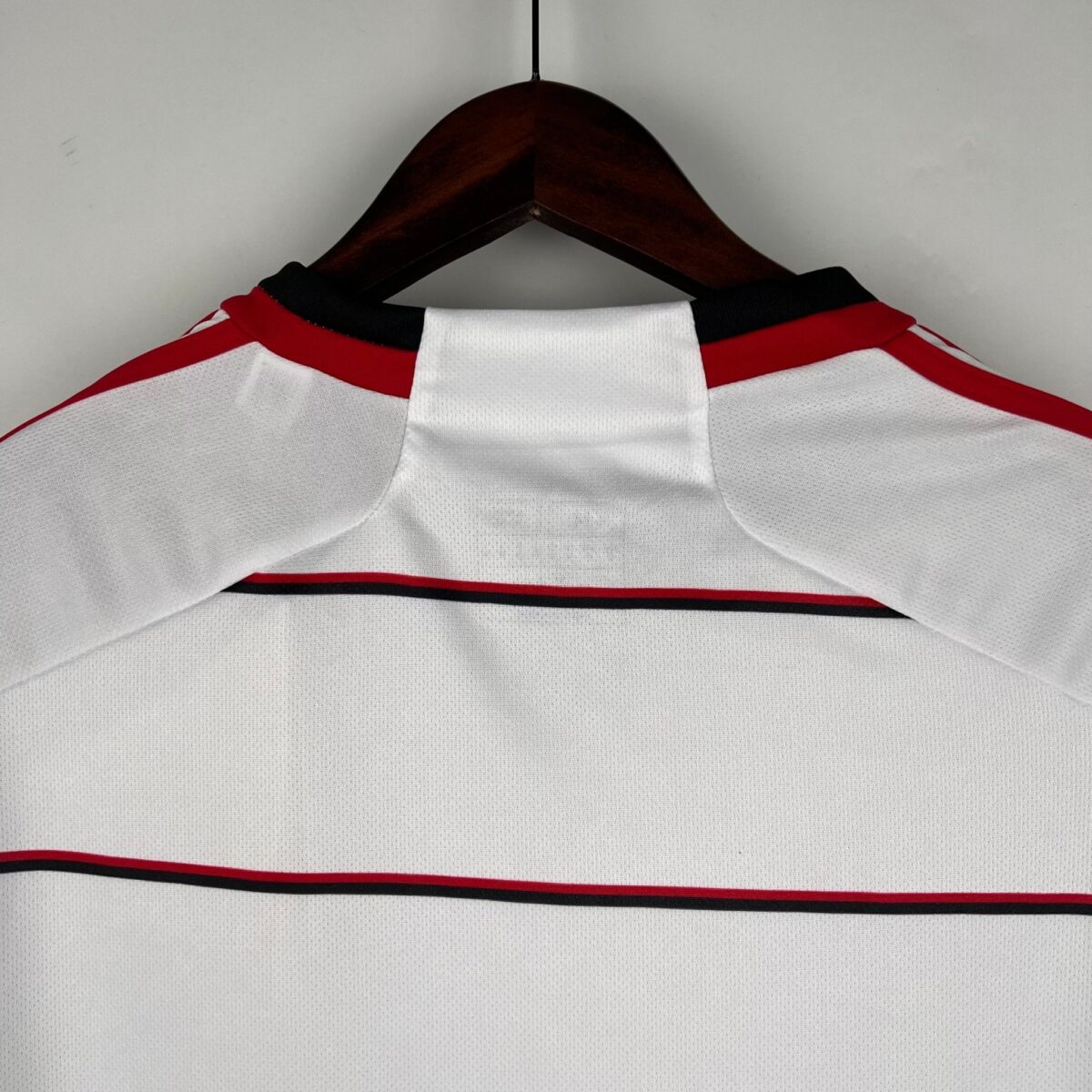 White football jersey with red and black stripes, collar detail visible.