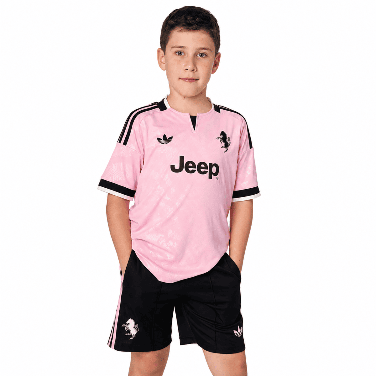 Young boy wearing Juventus away kit for kids 2026/27 in pink and black.