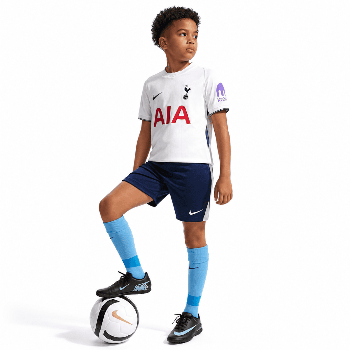 Child wearing Tottenham home kit 2026/27, white jersey, navy shorts, light blue socks, with a soccer.