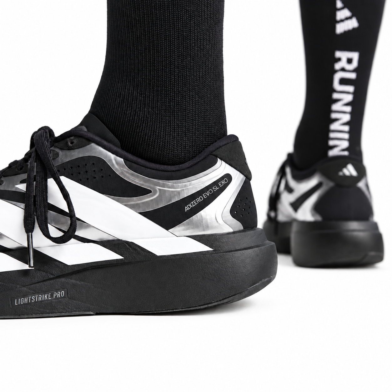 1bf202b7-1eaa-487a-95a1-fe5e03a7551f - UAE SPORT STORE Close-up of Adidas Adizero Evo SL EXO running shoes in black and white with black socks.