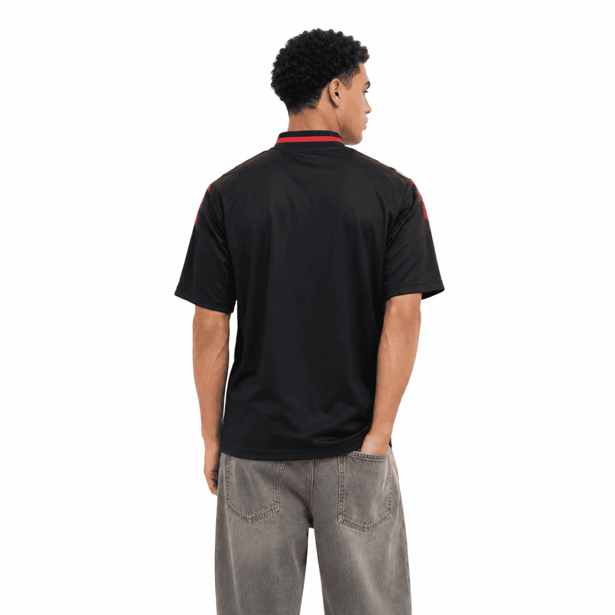 Man wearing black Manchester United lifestyle jersey, back view.