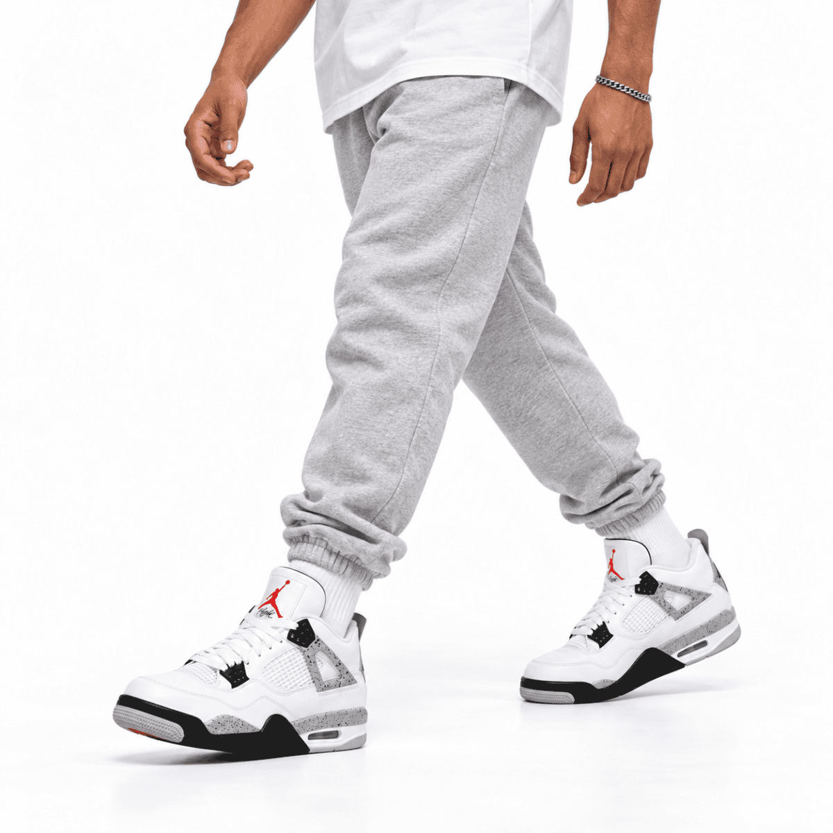 Person wearing white Air Jordan 4 Retro OG sneakers with gray sweatpants.