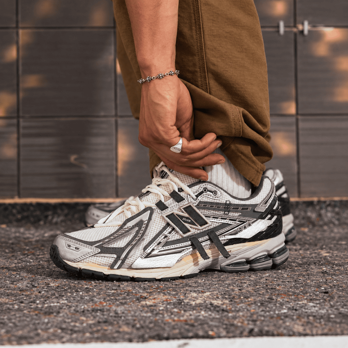 Person wearing New Balance 1906 Mesh-Panel Sneakers, beige and black, on asphalt.