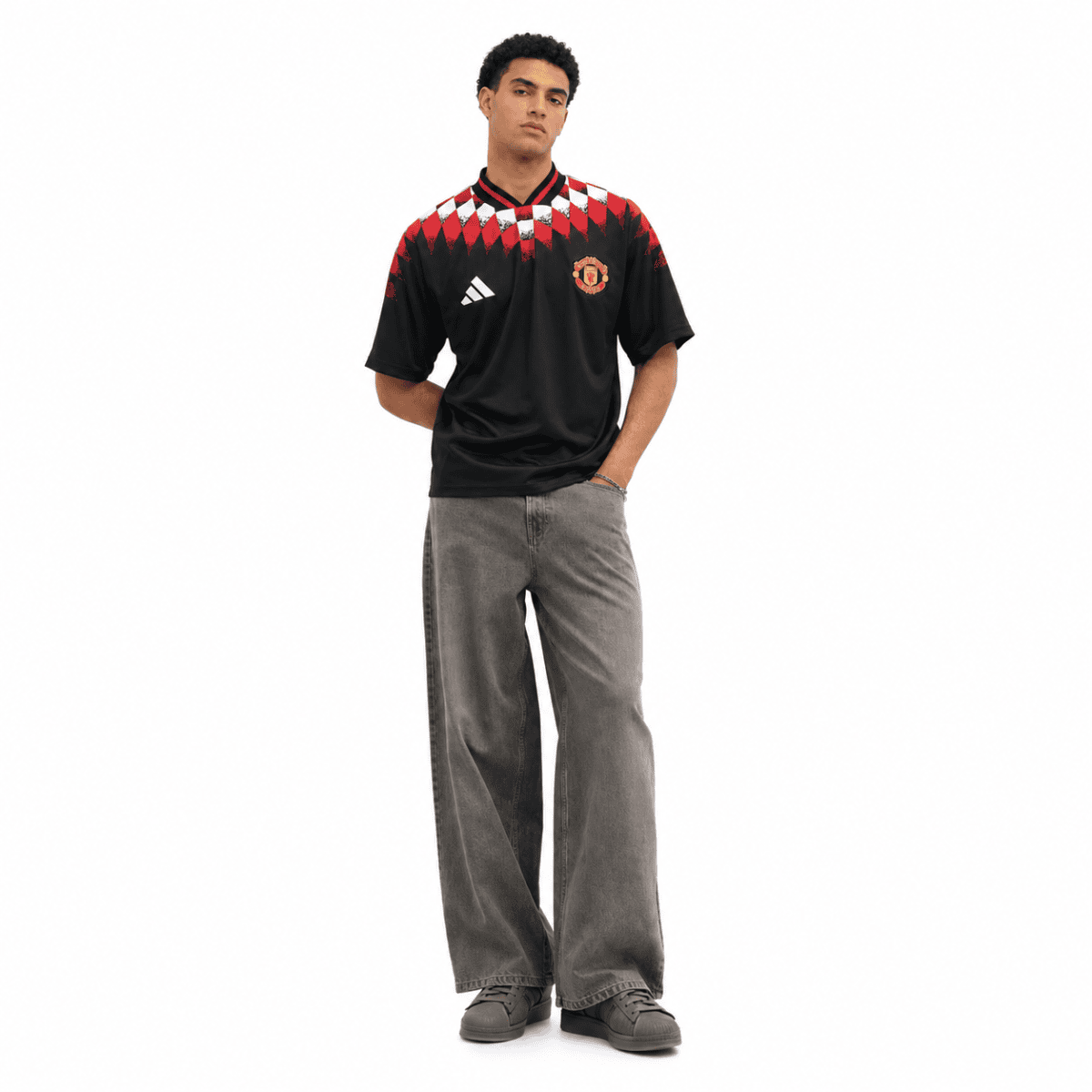Man wearing Manchester United black and red home jersey with grey pants.